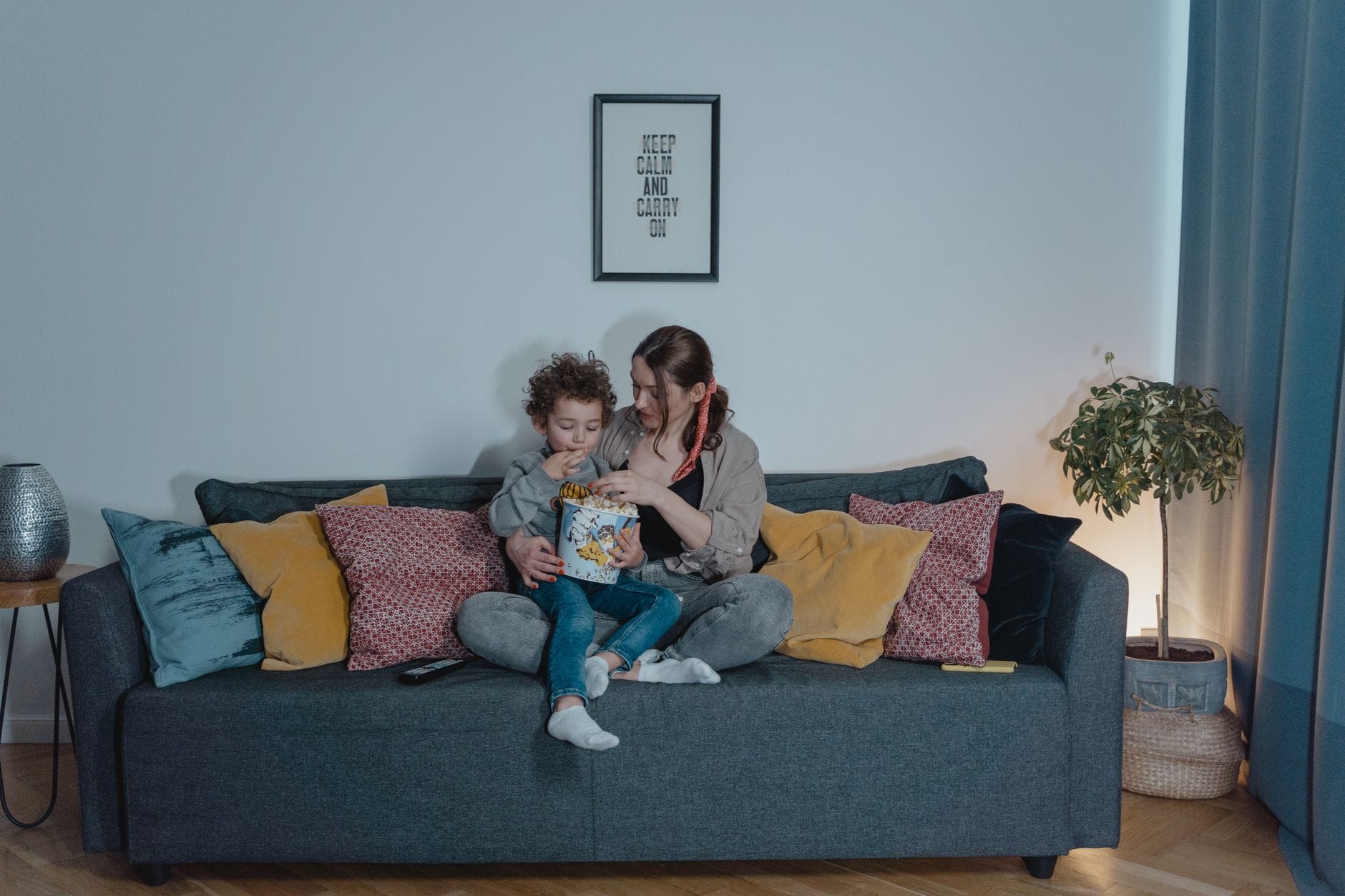 Mama z dzieckiem jedzą przekąski na przytulnej kanapie w salonie