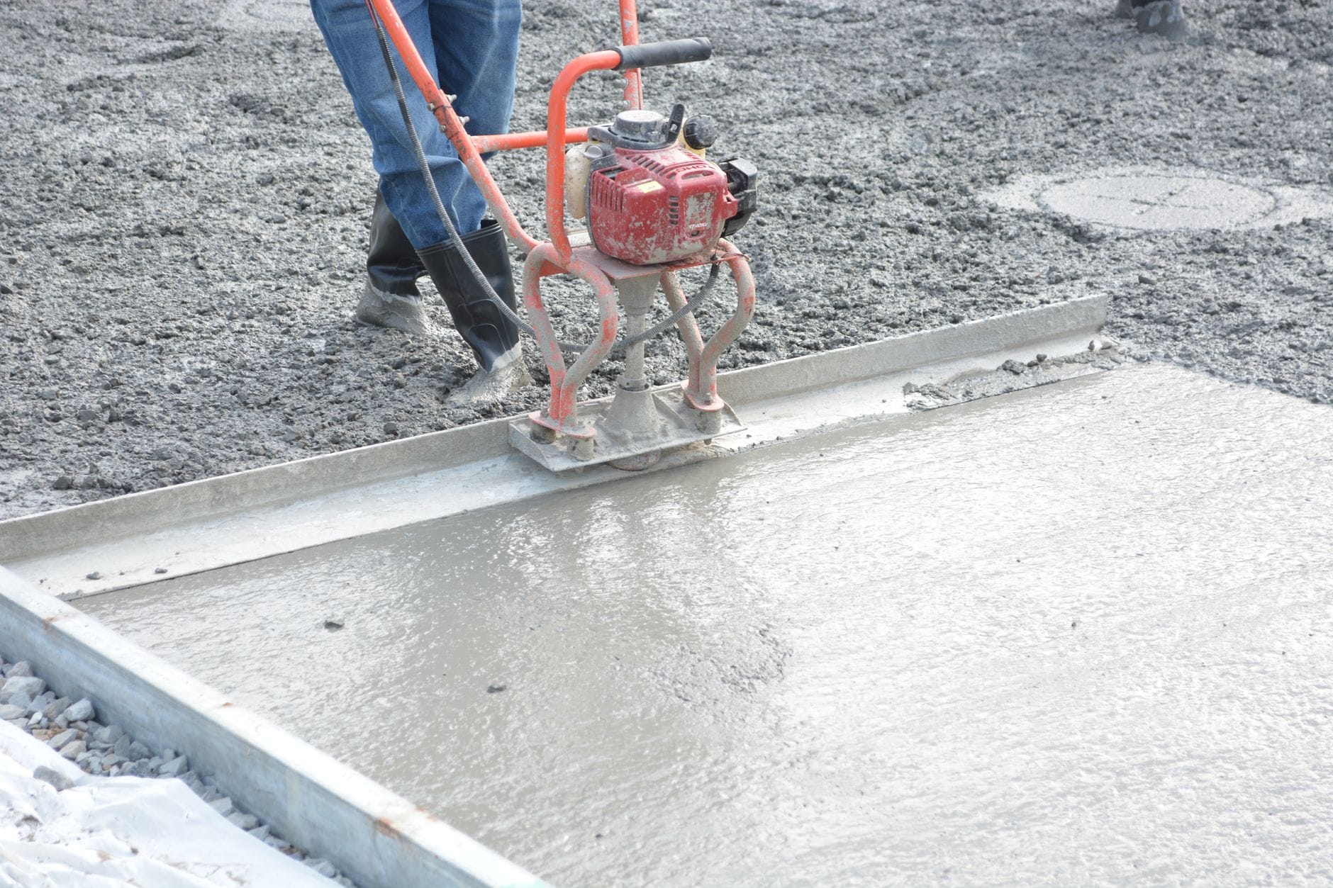 Pracownik zacierający świeży beton zacieraczką na budowie